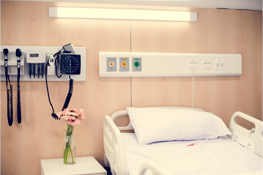 A hospital bed next to a vase of flowers